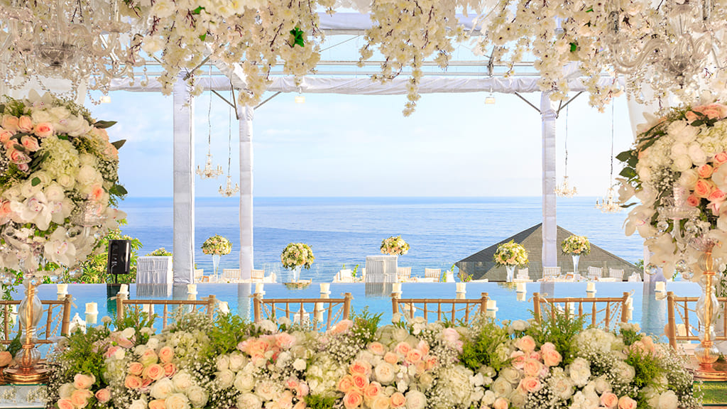Cérémonie de mariage avec vue sur l'océan et arche florale en roses blanches