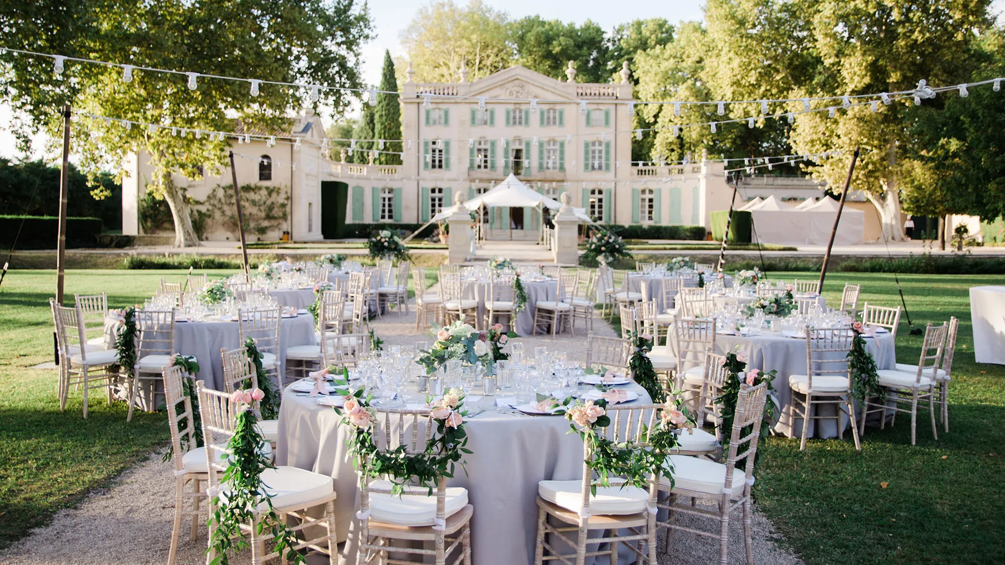 Réception de mariage en château avec tables blanches dans un jardin