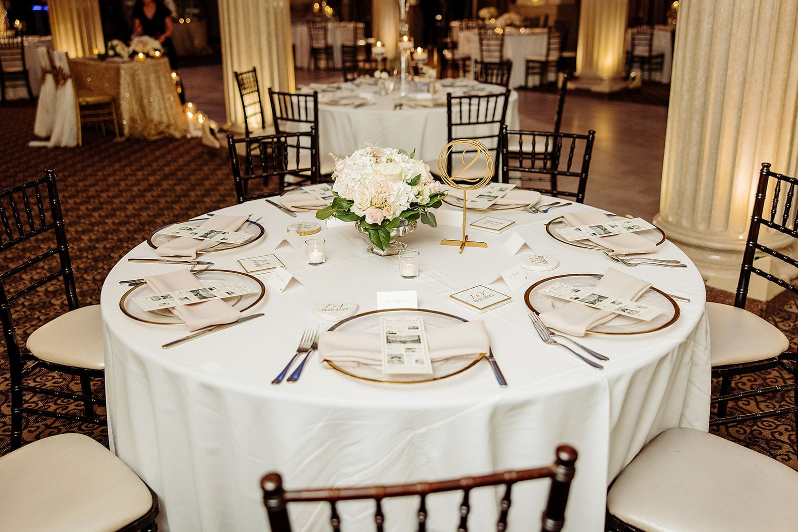 Table ronde de réception de mariage ornée de fleurs blanches et numéro de table en or
